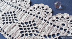 crocheted doily on blue fabric with water droplet next to it, closeup