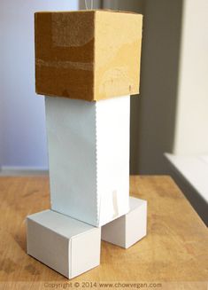 a cardboard box sitting on top of a wooden table next to a white square block