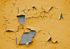 peeling paint on an old yellow wall that has been chipped off with some white paint