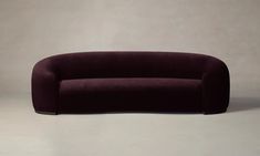 a purple couch sitting on top of a white floor next to a gray wall in front of it