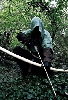 a man kneeling down in the woods with a bow and arrows attached to his back