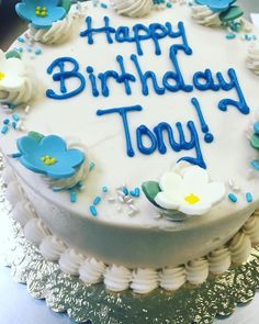 a birthday cake with white frosting and blue flowers on the top that says happy birthday tony