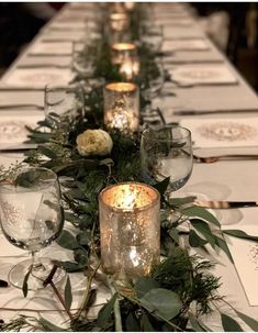 a long table with candles and greenery on it