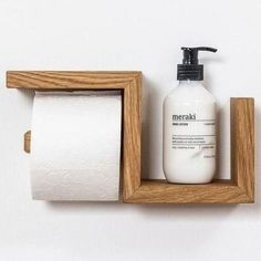 there is a bottle of soap and a roll of toilet paper in a wooden holder