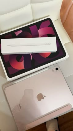 an apple laptop computer sitting on top of a white couch next to a person's legs