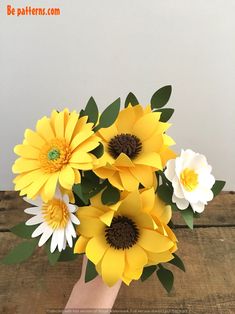 a hand holding a bouquet of yellow and white flowers