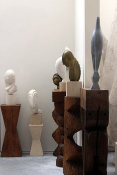 various sculptures are displayed on pedestals in an art gallery with white walls and concrete flooring