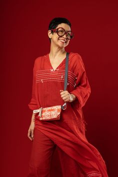 a woman in red is smiling and holding a handbag with her legs spread out