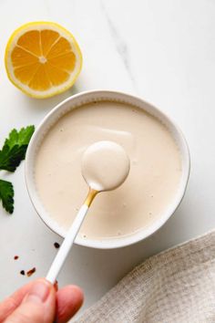 a hand holding a spoon over a bowl of yogurt