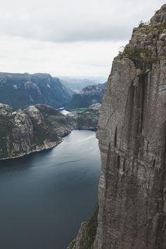 a man standing on top of a cliff next to a body of water