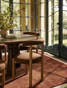 a dining room table with four chairs and a potted plant