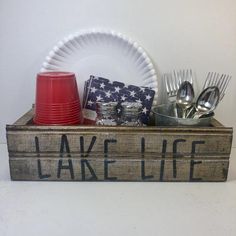 a wooden box with utensils and other items in it that says lake life