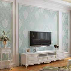 a living room with a large tv on top of a white entertainment center next to a window