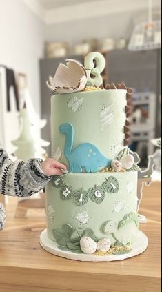 a person is decorating a three tiered cake with dinosaurs and seashells