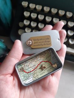 a person holding a small map with a keychain on it and a keyboard in the background