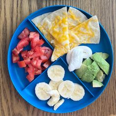 a blue plate topped with fruit and veggies on top of a wooden table