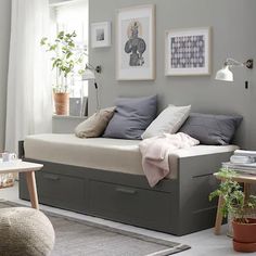 a white daybed sitting in a living room next to a chair and table with potted plants on it