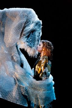 a woman standing in front of an ice sculpture with her face close to the ground