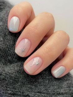 a mani with white and silver designs on the tip of it, sitting next to a gray sweater