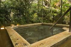 an outdoor hot tub surrounded by greenery and lights in the middle of a wooden deck