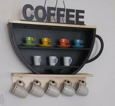 there are cups and mugs on the shelf next to the coffee cup holder that is hanging from the wall