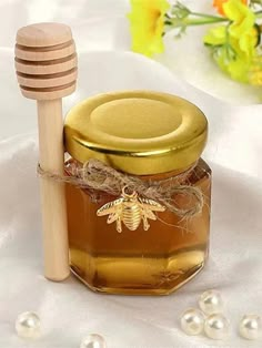 a jar of honey with a wooden stick in it sitting on a white tablecloth