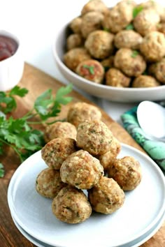 some meatballs are on a white plate and next to a bowl of dipping sauce