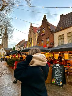 a woman is walking down the street with an umbrella over her head while looking at shops