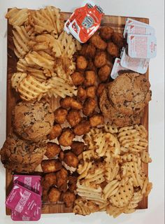 a wooden cutting board topped with different types of food and snacks on top of it