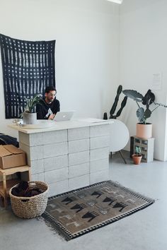 a man sitting at a desk with a laptop computer on it in front of a plant