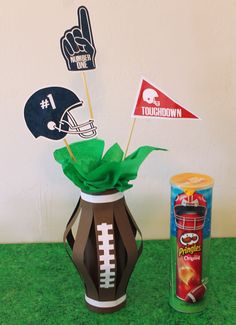 a football themed centerpiece next to a canister filled with tissue paper and flags