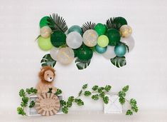 the balloon wall is decorated with green, white and gold balloons for a jungle themed birthday party