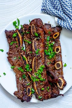 a white plate topped with meat covered in sauce and garnished with green onions