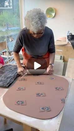 an older woman is working on a piece of art