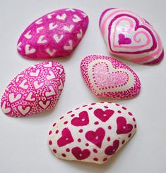 four pink and white hearts painted on rocks