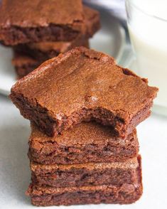 chocolate brownies stacked on top of each other with a glass of milk in the background