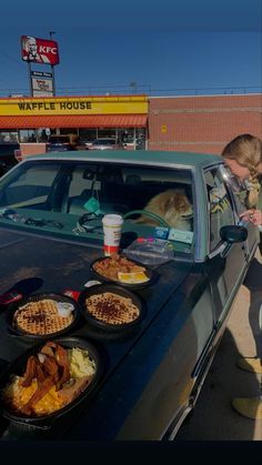 a man and his dog are getting food out of the back of a car at a waffle house