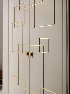 a white cabinet with gold handles and bars on the doors, next to a bed