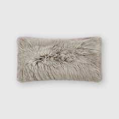 a gray furry pillow sitting on top of a white wall