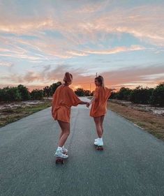 two girls rollerblading down an empty road at sunset