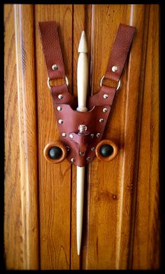 a wooden door with a brown leather mask on it's face and eyeballs attached to the handle