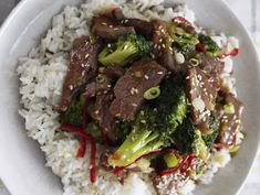 a white plate topped with beef and broccoli covered in sauce on top of rice