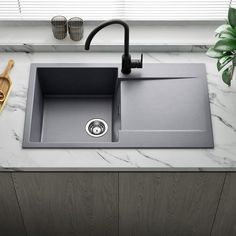 a kitchen sink sitting on top of a counter next to a cutting board and wooden utensils