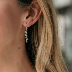 a close up of a woman's ear wearing gold earrings with leaves on them