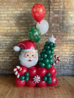 a santa clause balloon sculpture sitting on top of a table next to some christmas balloons