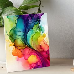 a colorful abstract painting on a white background art boarder next to a potted plant