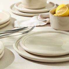 the table is set with plates, silverware and lemon wedges on it's placemats