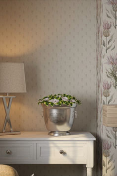 a flower pot sitting on top of a white table next to a lamp and chair