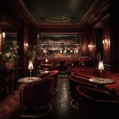 a dimly lit bar with red velvet seating