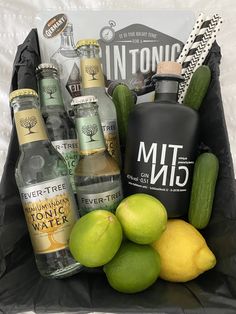 a basket filled with bottles and lemons next to cucumbers